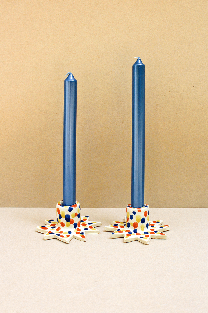 pair of mulicolor star shaped ceramic candleholders with blue candles