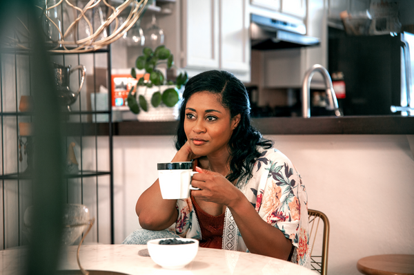 photograph of woman drinking coffee seated at dining table